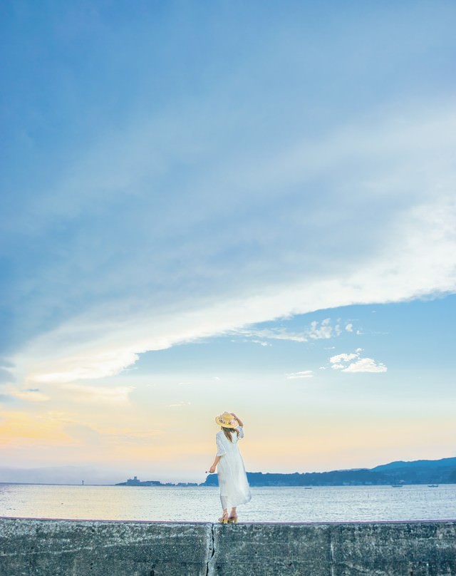 堤防に立ち海を見ている麦わら帽子の女性の写真 画像 フリー素材 ぱくたそ